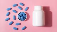 White PrEP bottle with blue PrEP pills against pink background